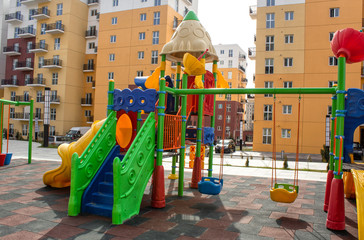 Children's playground with slides and swings in the courtyard of residential buildings.