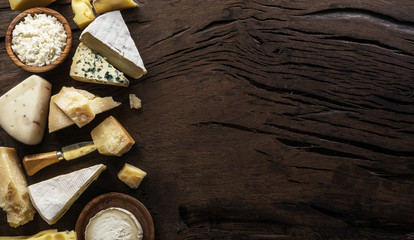 Assortment of different cheese types on wooden background. Top view.