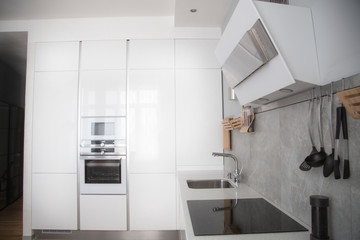 white metal hood in the white kitchen. built-in kitchen in the wall with white applianceswhite metal hood in the white kitchen. built-in kitchen in the wall with white appliances