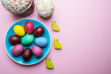Colorful Easter eggs and Easter bread attributes of Easter celebration. Pink background.