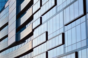 New office building in business center. Wall made of steel and glass with blue sky. 