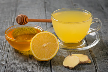 A Cup of ginger root drink and a Cup of honey on a wooden table. A tool to fight viruses.