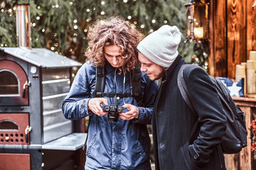 Two Young friends strolling through the Christmas fair with a camera