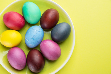 Colorful Easter eggs as an attribute of Easter celebration on the yellow plate.