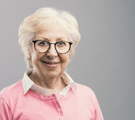 Happy senior woman posing on gray background