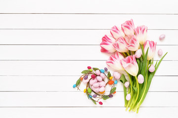 Easter background. Decorative Easter eggs and pink tulips on white background. Copy space, top view.