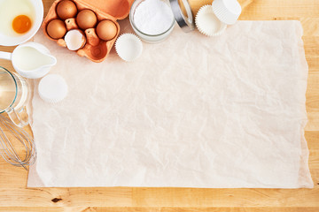 Food ingredients and kitchen utensils on crumpled piece of white parchment or baking paper on...
