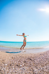 Girl in a bathing suit jumping on the beach.