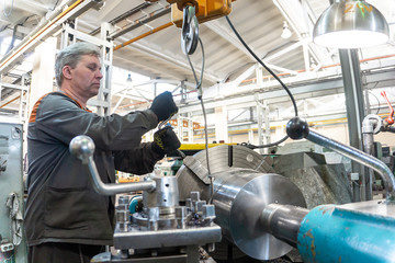 Turner worker manages the metalworking process of mechanical cutting on a lathe.