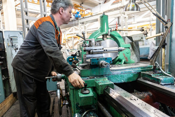 Turner worker manages the metalworking process of mechanical cutting on a lathe.