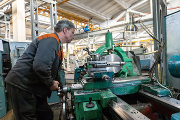 Fototapeta na wymiar Turner worker manages the metalworking process of mechanical cutting on a lathe.