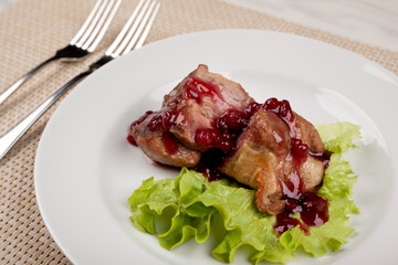 Fried meat with red cherry sauce on a white plate.