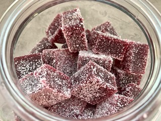 Cubes of marmalade from currants, burgundy, in sugar, lie on the table.