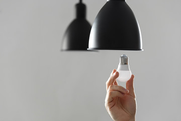 Changing the bulb for led bulb in floor lamp in black colour. On light gray background