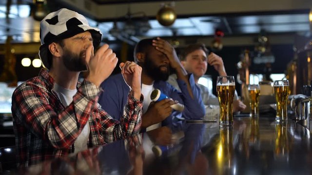 Football fans watching match in pub, frustrated with missed goal, losing game