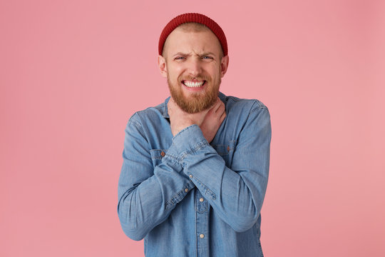 Bearded man squeezes constrict with his hands the neck, especially so as to cause death, closed eyes, makes a suicide gesture, strangles himself, over pink background