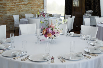 Event white restaurant table served and decorated with delicate fresh flowers