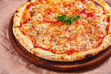 Italian Pizza Margherita with tomatoes and mozzarella cheese on wooden cutting board. Close up