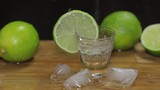 Pouring vodka or tequila into shot glasses with ice cubes