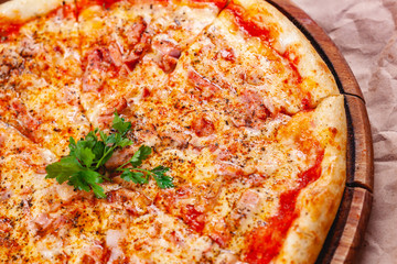 Italian Pizza with bacon, tomatoes and mozzarella cheese on wooden cutting board. Close up