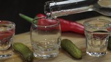 Pour vodka into shot glasses placed on a wooden board