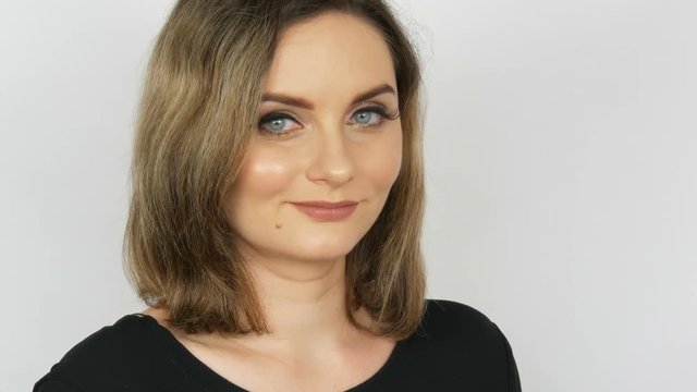 The beautiful sexy girl a bitch with flowing hair and blue eyes reproachfully looks into the camera on a white background