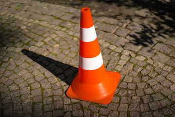Close-up of striped orange and white road cone on pavement. Bright orange traffic cone for parking...