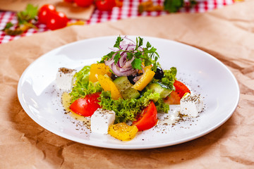 Greek salad with vegetables and feta cheese on white plate. Close up