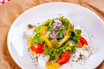 Greek salad with vegetables and feta cheese on white plate. Close up