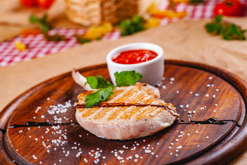 Rack of lamb with tomato sauce on wooden cutting board. Close up
