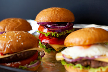 juicy burgers with beef patty and fresh vegetables; consists of: buns, sweet sauce, onion rings, sweet pepper, lettuce, cheese, eggs