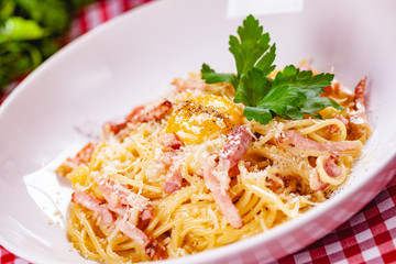 Spaghetti Carbonara with bacon, yolk and cheese on white plate. Close up