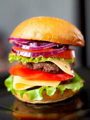 juicy burger with two pork cutlets and fresh vegetables; It consists of: buns, sweet sweet sauce, onion, pepper, tomatoes, green salad and cheese
