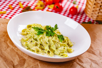 Italian Pasta tagliatelle with pesto sauce and parmesan cheese on white plate. Close up