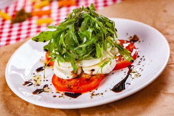 Caprese salad with arugula on white plate. Close up