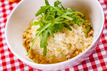 Risotto with gorgonzola, walnuts and arugula on white plate. Close up
