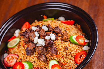 Traditional uzbek pilaf with meat, vegetables and garlic. Close up