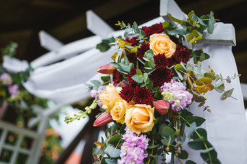 Wedding arch with fresh flower decoration in yellow and bordo.