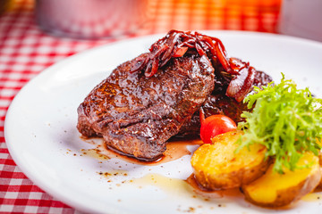 Grilled beef steak served with potato on white plate. Close up