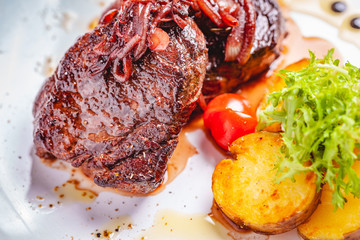Grilled beef steak served with potato on white plate. Close up