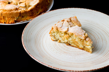 Аpple pie on a plate on a black background. Сharlotte