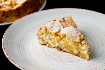 Аpple pie on a plate on a black background. Сharlotte
