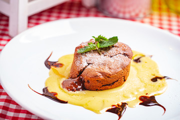 Chocolate fondant served with custard cream on white plate. Lava cake recipe. Close up
