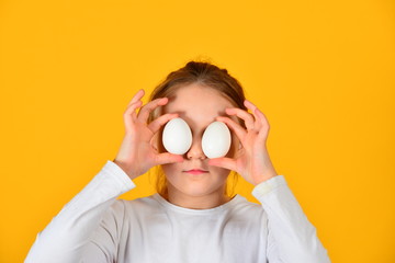 Joyful and cheerful girl holding Easter eggs in her eyes