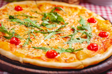 Pizza Margherita (Margarita) with fresh arugula on wooden board. Close up