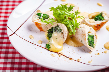 Steamed chicken cutlets stuffed with spinach on white plate. Close up