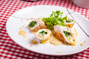 Steamed chicken cutlets stuffed with spinach on white plate. Close up