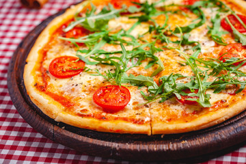 Pizza Margherita (Margarita) with fresh arugula on wooden board. Close up