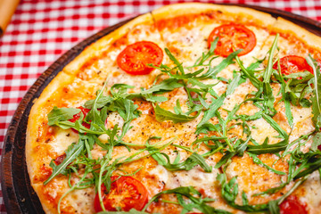 Pizza Margherita (Margarita) with fresh arugula on wooden board. Close up