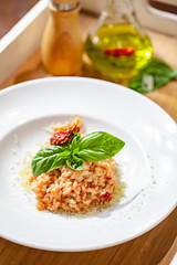 Risotto with sun-dried tomatoes and capers on white plate. Close up